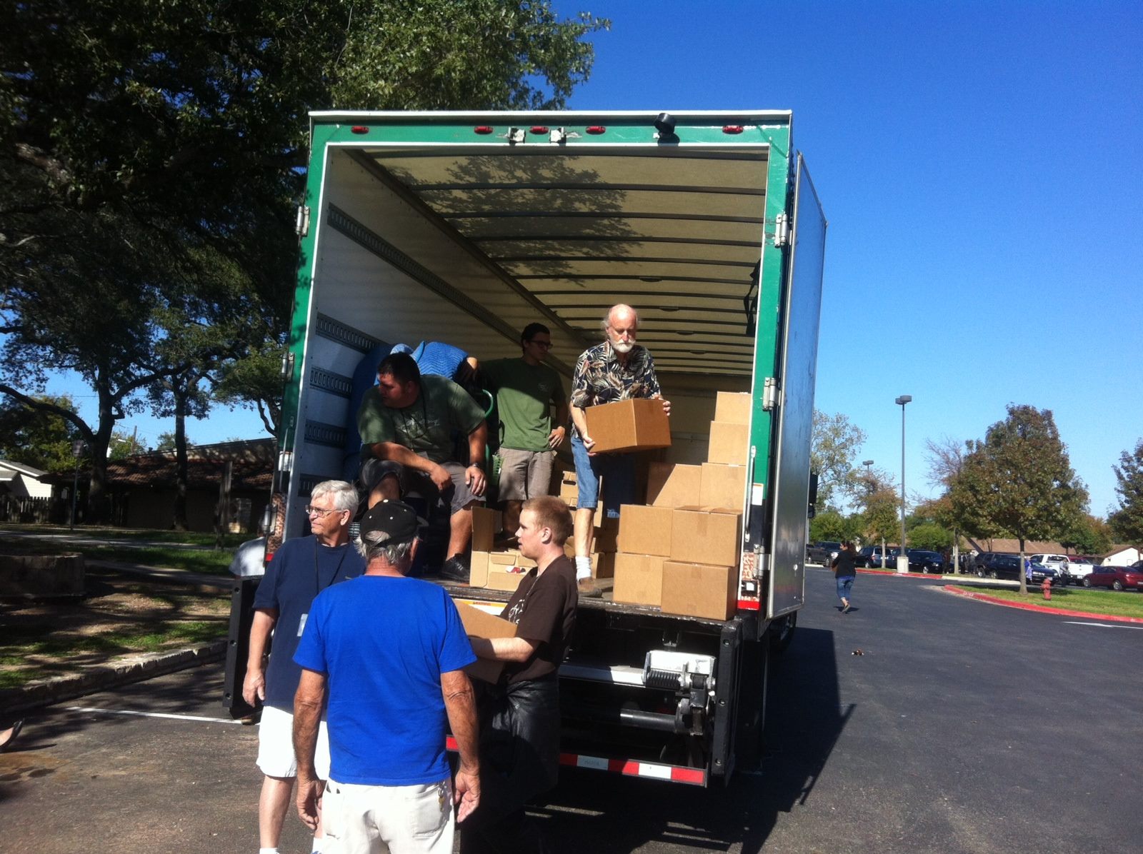 Movers and food bank volunteers moving boxes of food out of Little Guys Movers truck