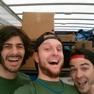 three movers in a truck smiling for the camera