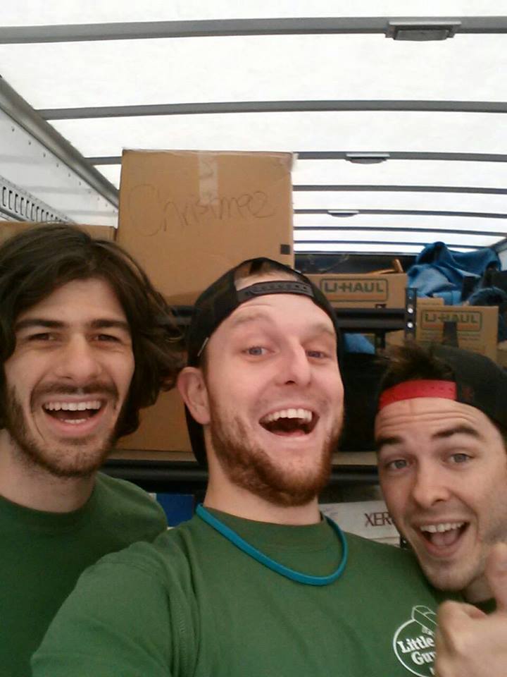 three movers in a truck smiling for the camera