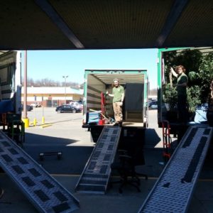 Three moving trucks with ramps lowered and movers inside