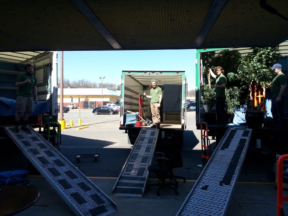 Three moving trucks with ramps lowered and movers inside