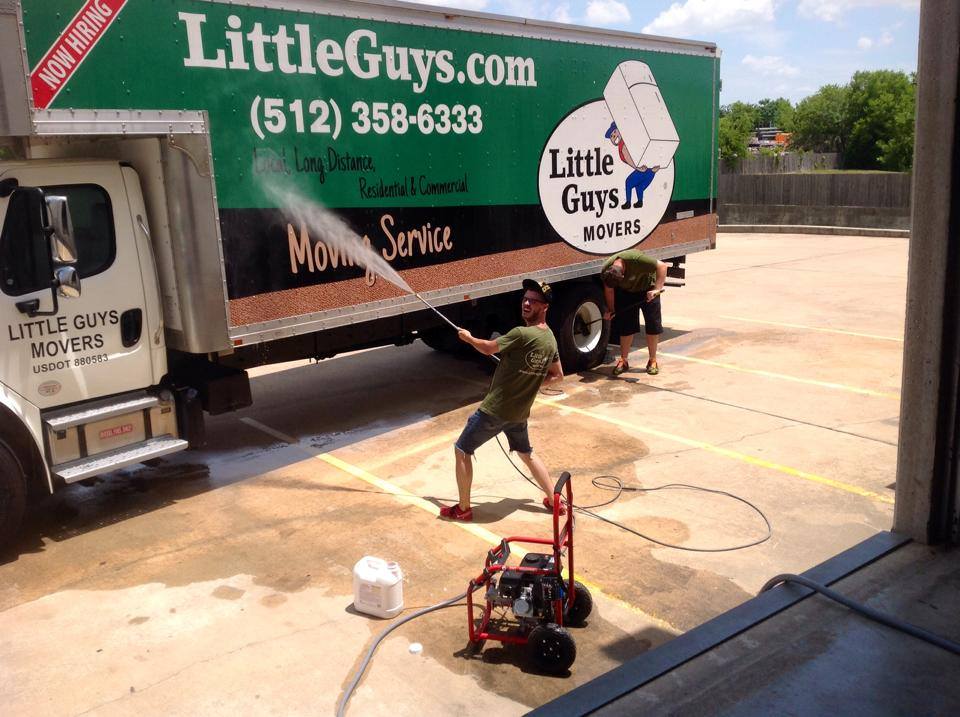 Man powerwashing Little Guys Movers truck