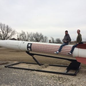 Two men sitting on large rocket