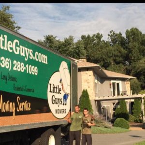 Two movers standing next to a moving truck, smiling and giving thumbs up