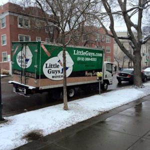 A Little Guys Movers truck parked next to a snowy sidewalk