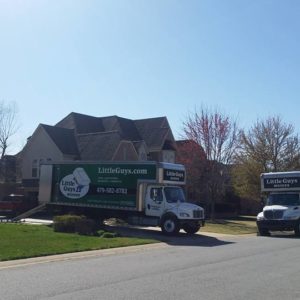 Two Little Guys Movers trucks in a residential neighborhood