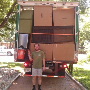 A Little Guy stands behind a moving truck