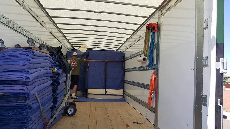 View of the back of a well-stocked moving truck with plenty of moving blankets stacked up
