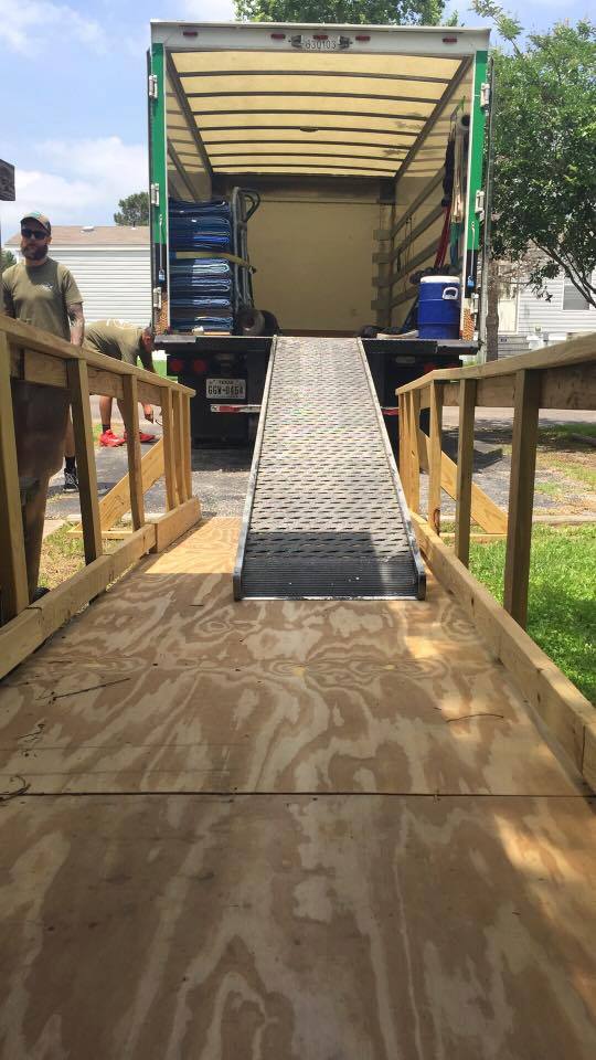 View of the back of a moving truck with its door open and loading ramp pulled out