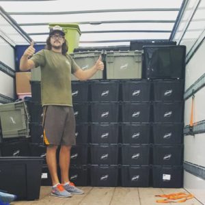 A Little Guy gives thumbs up next to neatly stacked crates