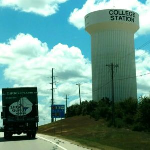 A Little Guys moving truck driving past the College Station water tower
