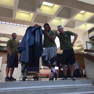 Little Guys Movers posing with a piece of furniture during a move