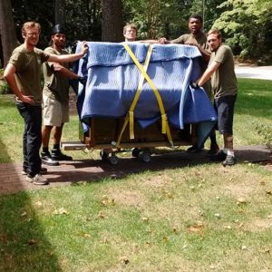 Five movers pose with well-wrapped furniture