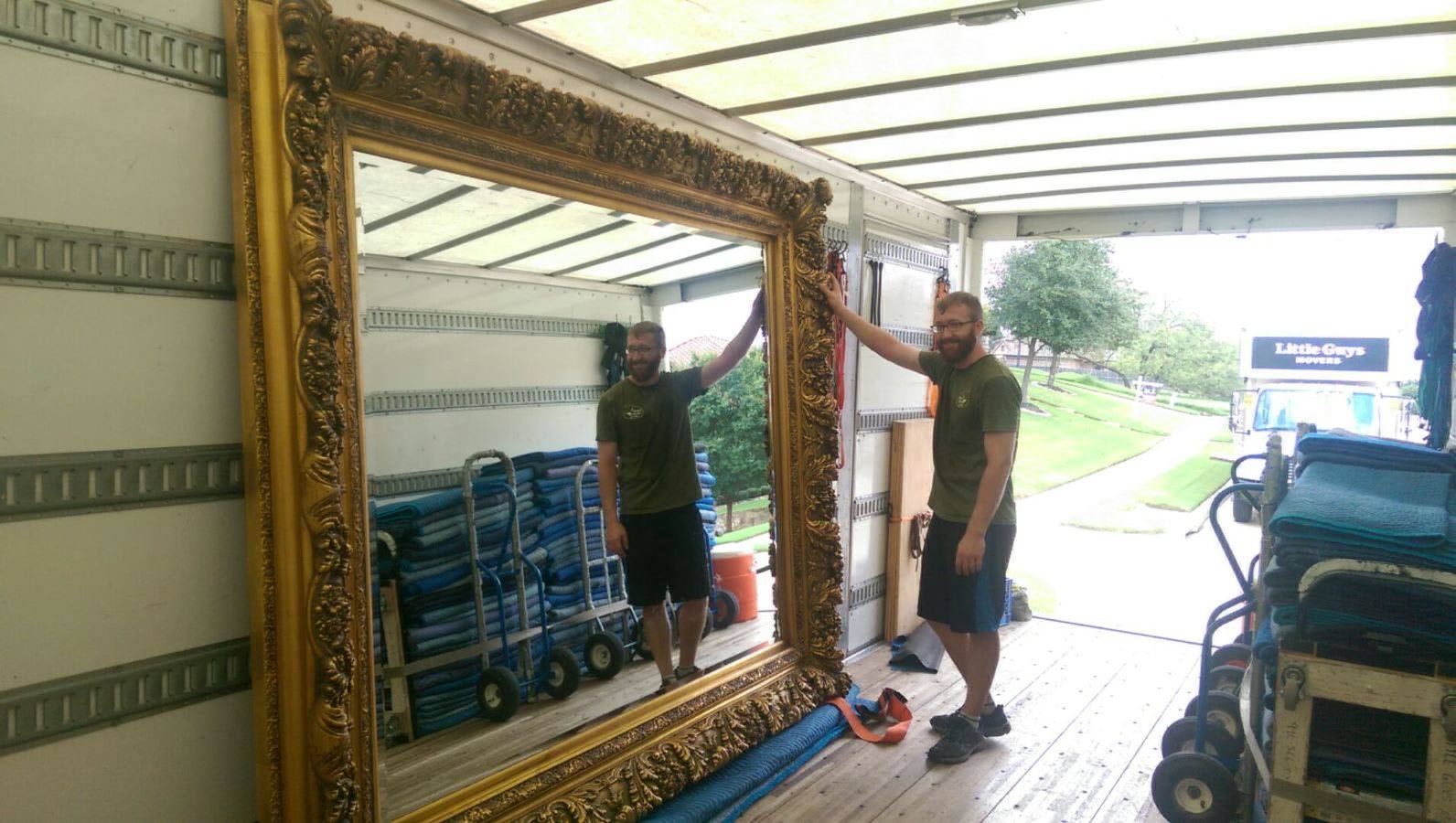 Little Guys mover loading a huge decorative mirror into the truck