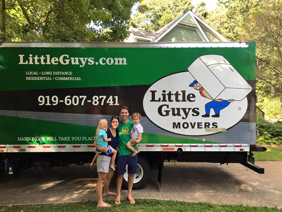 A happy family posing with a Little Guys Movers truck