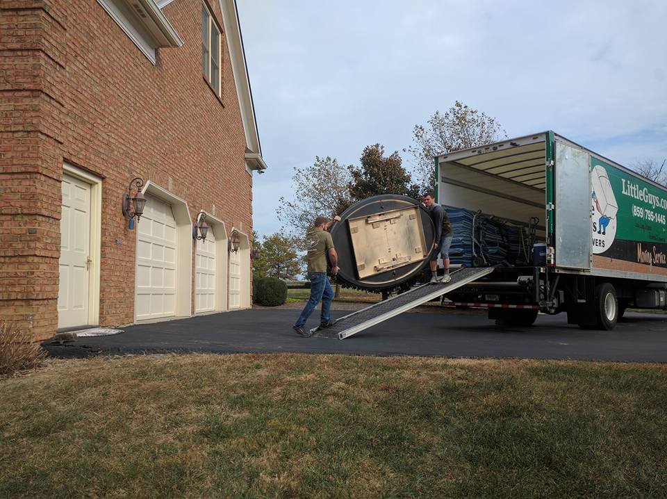 Two movers loading a table top into a truck