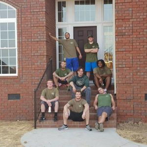 A crew of movers posing in front of a residence