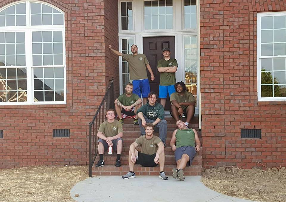 A crew of movers posing in front of a residence