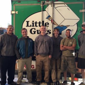 A crew of Little Guys Movers standing in front of a moving truck