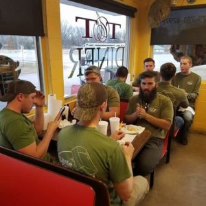 A crew of Little Guys seated in booths at a diner