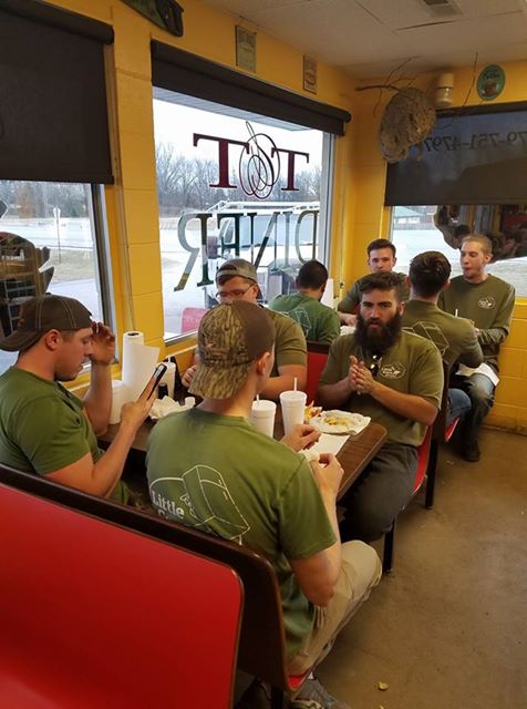 A crew of Little Guys seated in booths inside of a restaurant