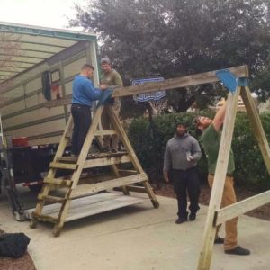 A Little Guys crew disassembles a kid's playset in a driveway near the truck