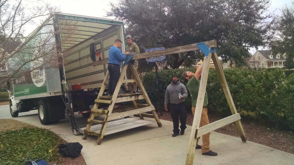 A Little Guys crew disassembles a kid's playset in a driveway near the truck