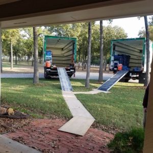 Two Little Guys trucks with their ramps backed up to a customer's front porch