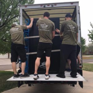 Several Little Guys Movers loading a safe into a moving truck