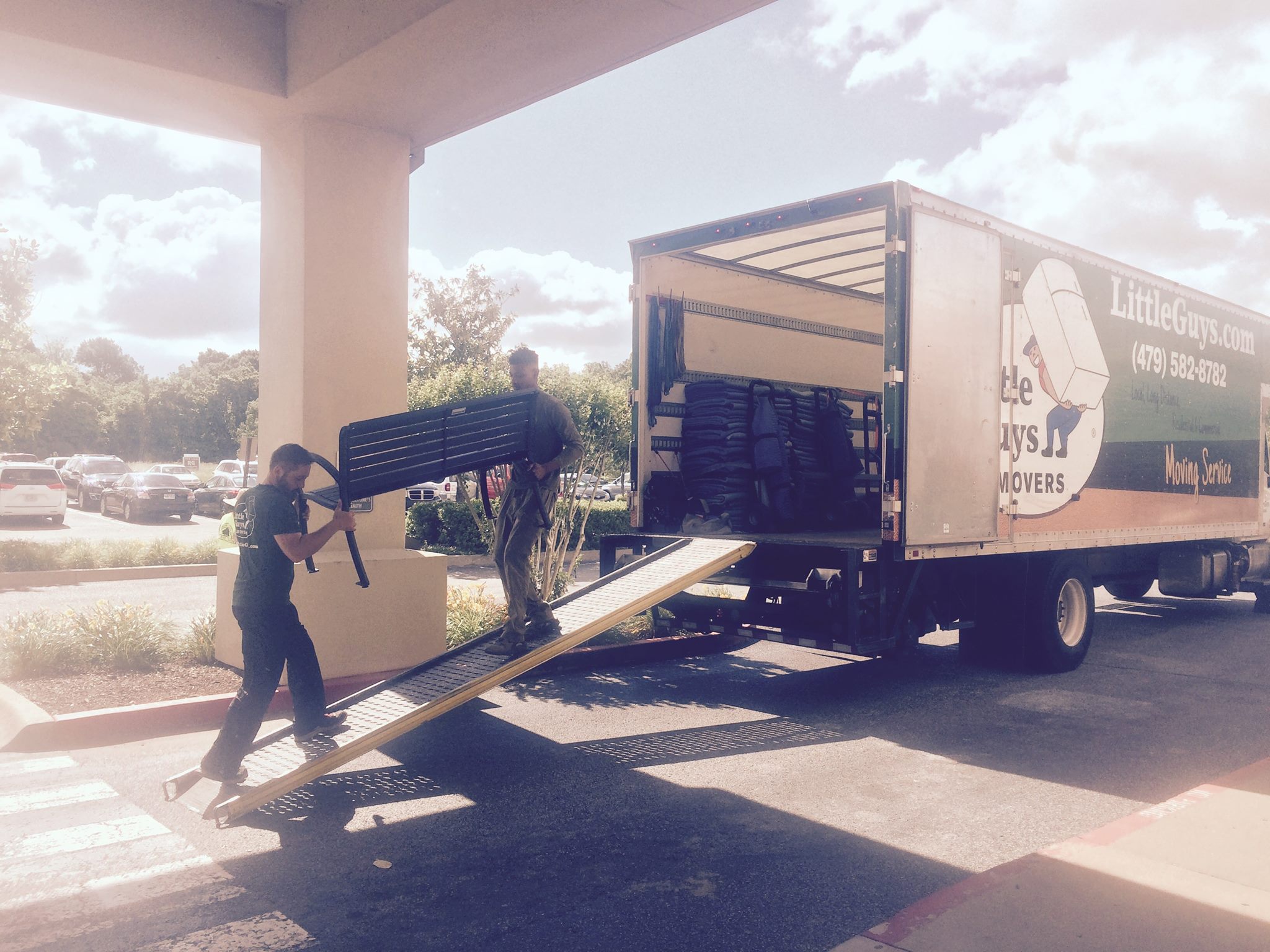Two movers loading a bench into the truck