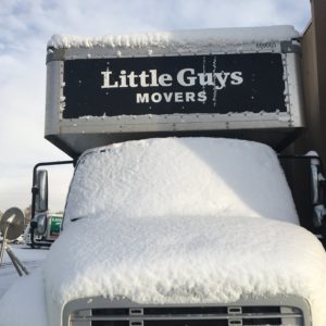 A Little Guys Movers truck covered in snow