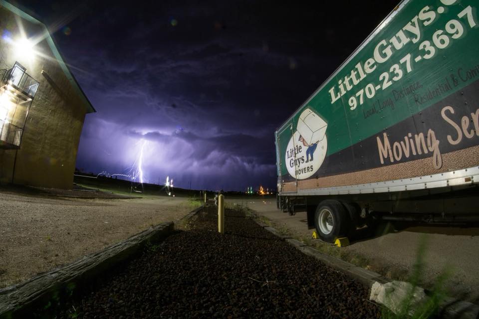 A Fort Collins Little Guys truck with a lightning flash in a night sky