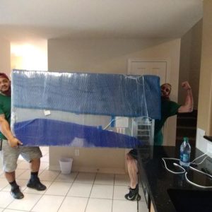 Two Little Guys Movers carrying a refrigerator