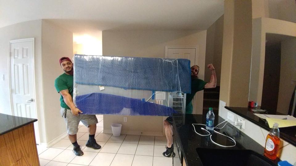 two movers holding refrigerator in kitchen