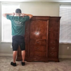 College Station mover in a Little Guys shirt with an armoire