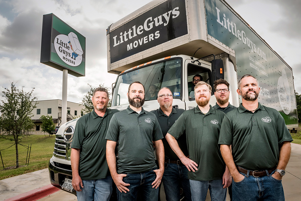 The Little Guys Movers Leadership Team stands in front of the Denton, Texas location. A moving truck is behind them.