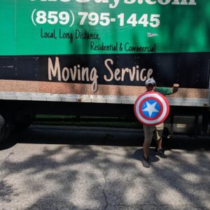 man holding captain america shield in front of little guys movers lexington truck