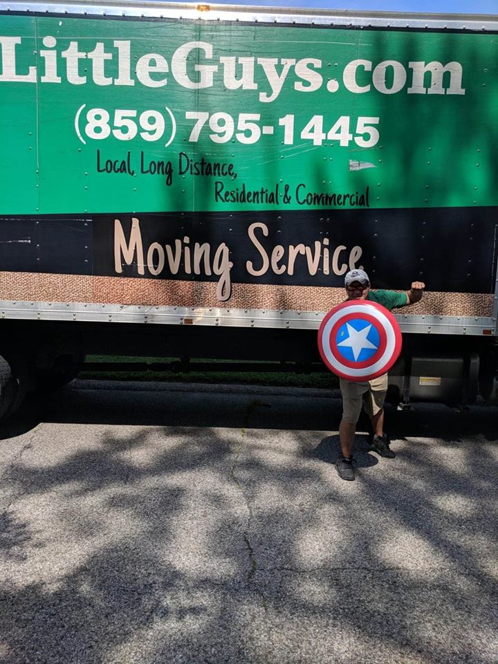 man holding captain america shield in front of little guys movers lexington truck