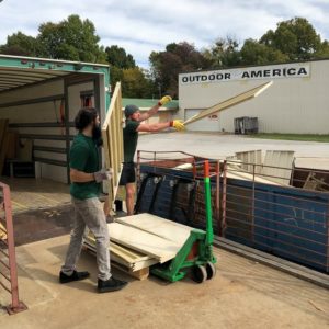 little guys movers throw old wood into a dumpster for habitat for humanity washington county