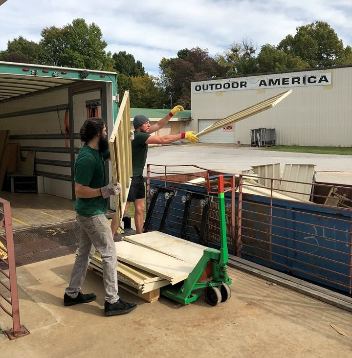 little guys movers throw old wood into a dumpster for habitat for humanity washington county
