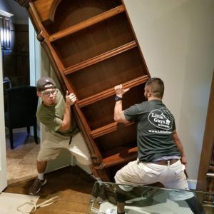 two movers lifting a bookcase