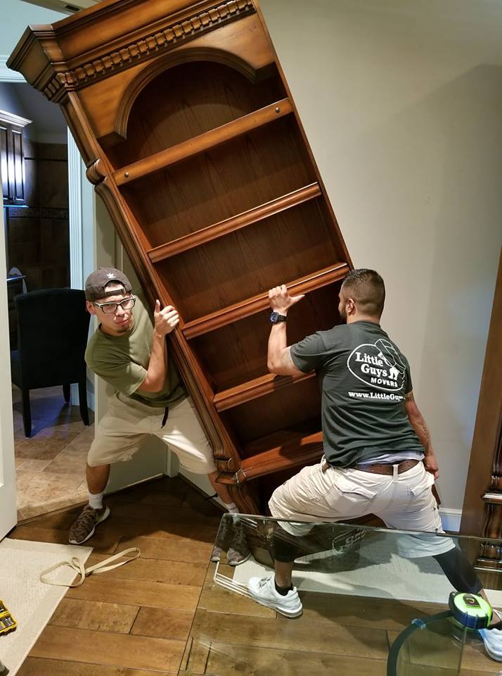 two movers lifting a bookcase