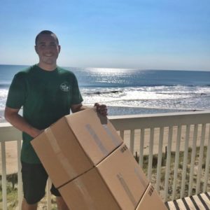 long distance movers holding boxes in front of ocean
