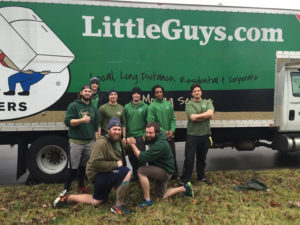 A team of Little Guys Movers in the Nashville, TN area pose for a picture in front of a green Little Guys truck.