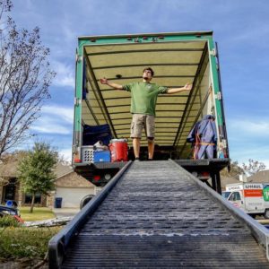 Greensboro mover standing in moving truck with arms wide