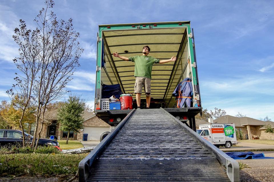 Greensboro mover standing in moving truck with arms wide