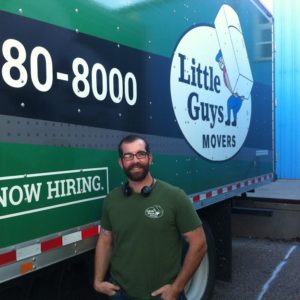 Little Guys Movers Gainesville new Branch Manager, Rusten Bullard in front of a Little Guys Movers moving truck.