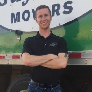 Lubbock Branch Manager Drew Brannon smiles in front of a Little Guys Movers moving truck