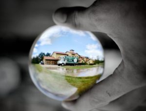 close up of a hand (in black and white) holding a "crystal ball" with an all-color image of a Little Guys Movers truck.