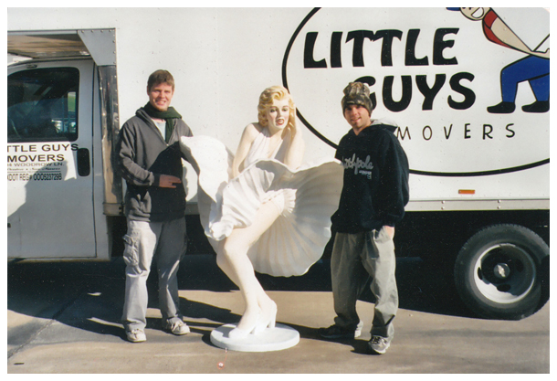 two Little Guys pose next to a lifesize Marilyn Monroe statue in front of an old LGM moving truck